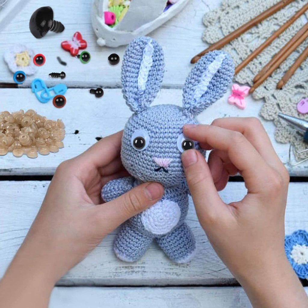 Crochet bunny with attached black safety eyes and hands placing snap-in eye piece