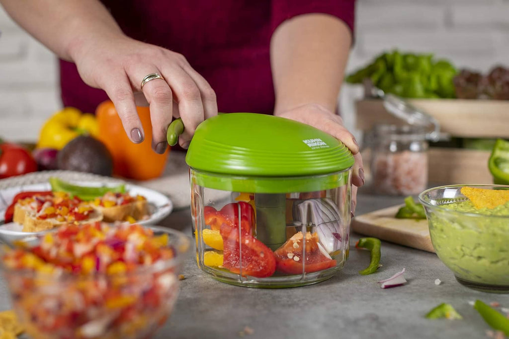 Green pull-cord food chopper on countertop with chopped ingredients inside clear bowl
