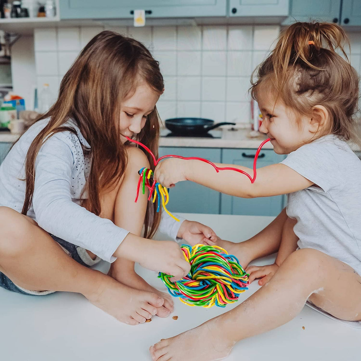Rainbow string licorice candy ball being shared by two children
