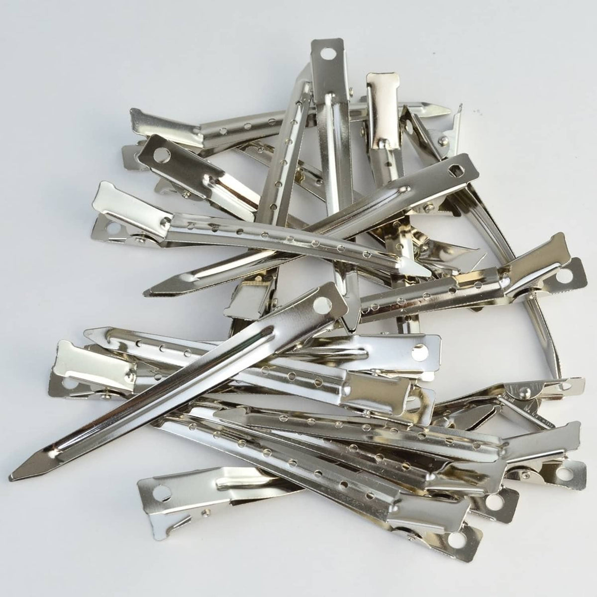 Pile of metal duck-bill clips with alligator-style grips and latch tabs