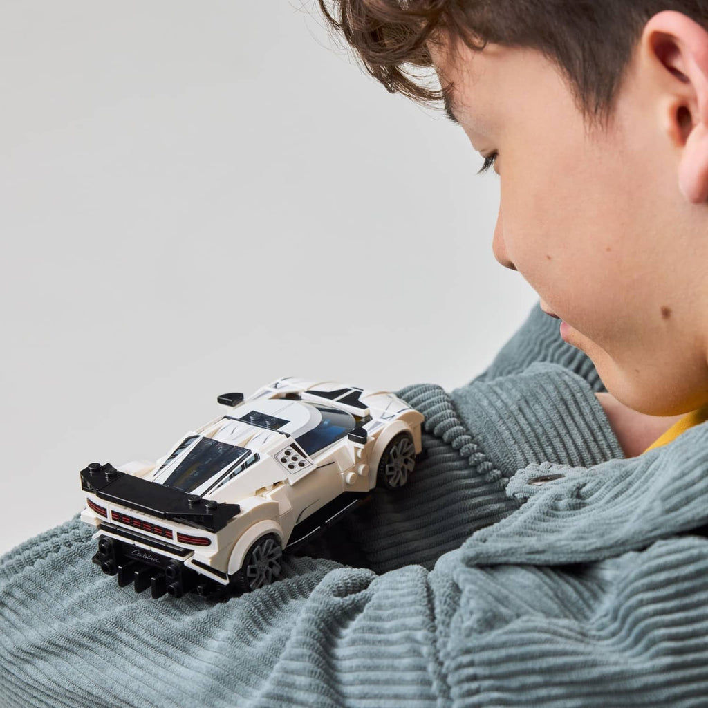 White LEGO toy sports car held by a child, side view close-up