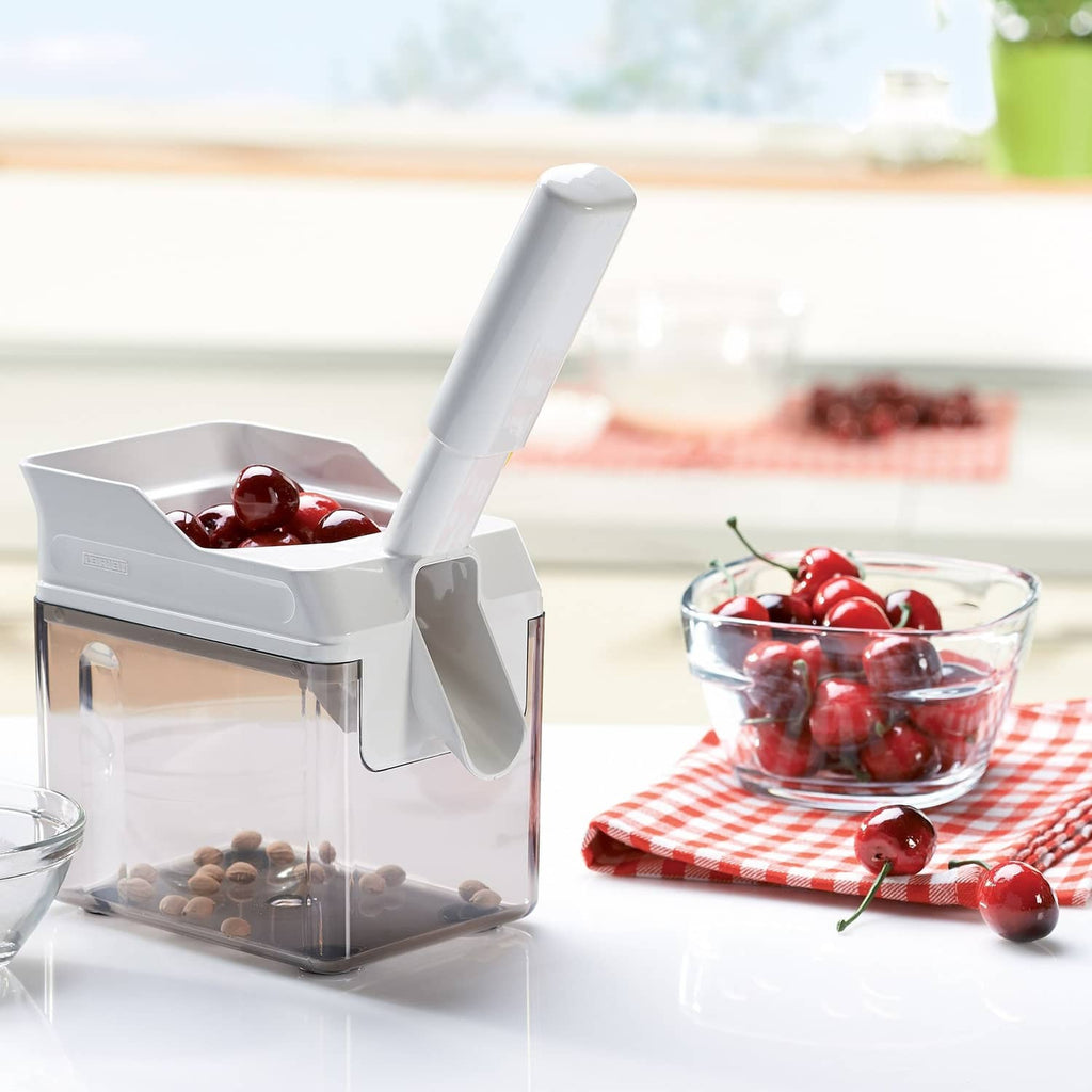 White Leifheit cherry stone remover with red cherries in hopper and lever handle