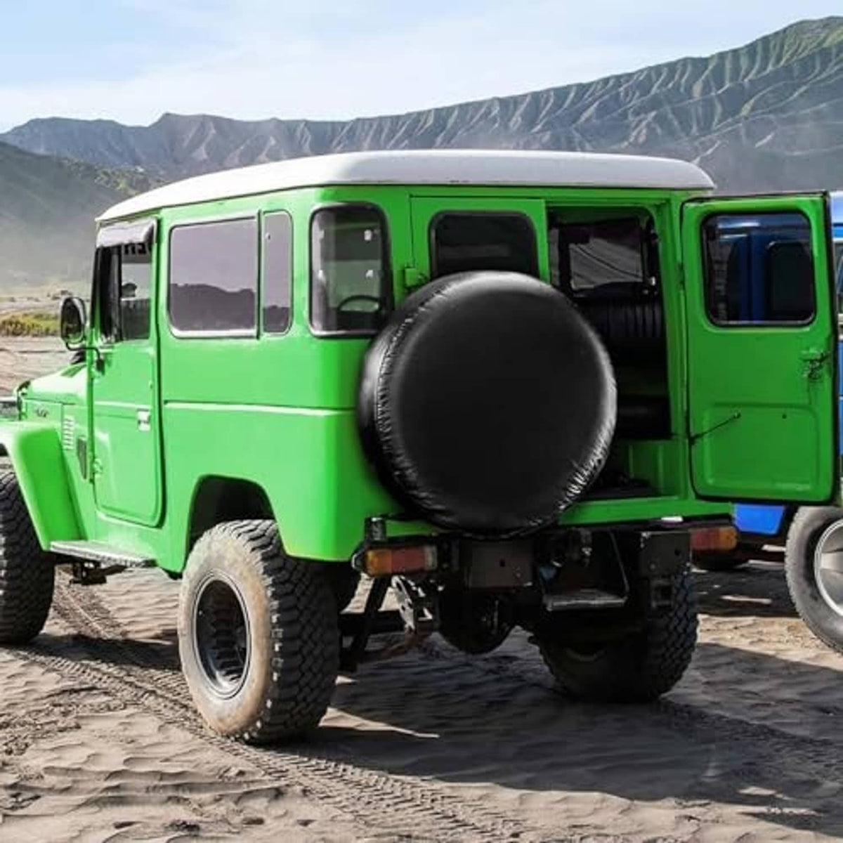 Black spare tire cover mounted on the front of a green off-road vehicle
