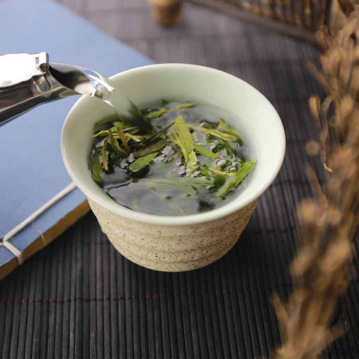 Green tea infusion in ceramic cup with floating tea leaves