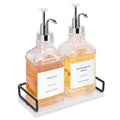 Two clear glass syrup bottles with chrome pumps and amber liquid on tray