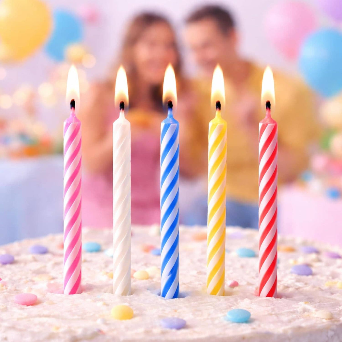 Five lit striped birthday candles in pink, white, blue, yellow, and red