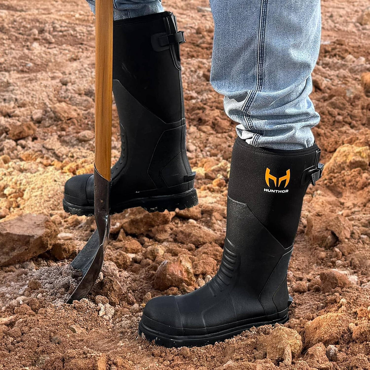 Black waterproof work boots standing on rocky ground, side view with HUNTHOR logo.