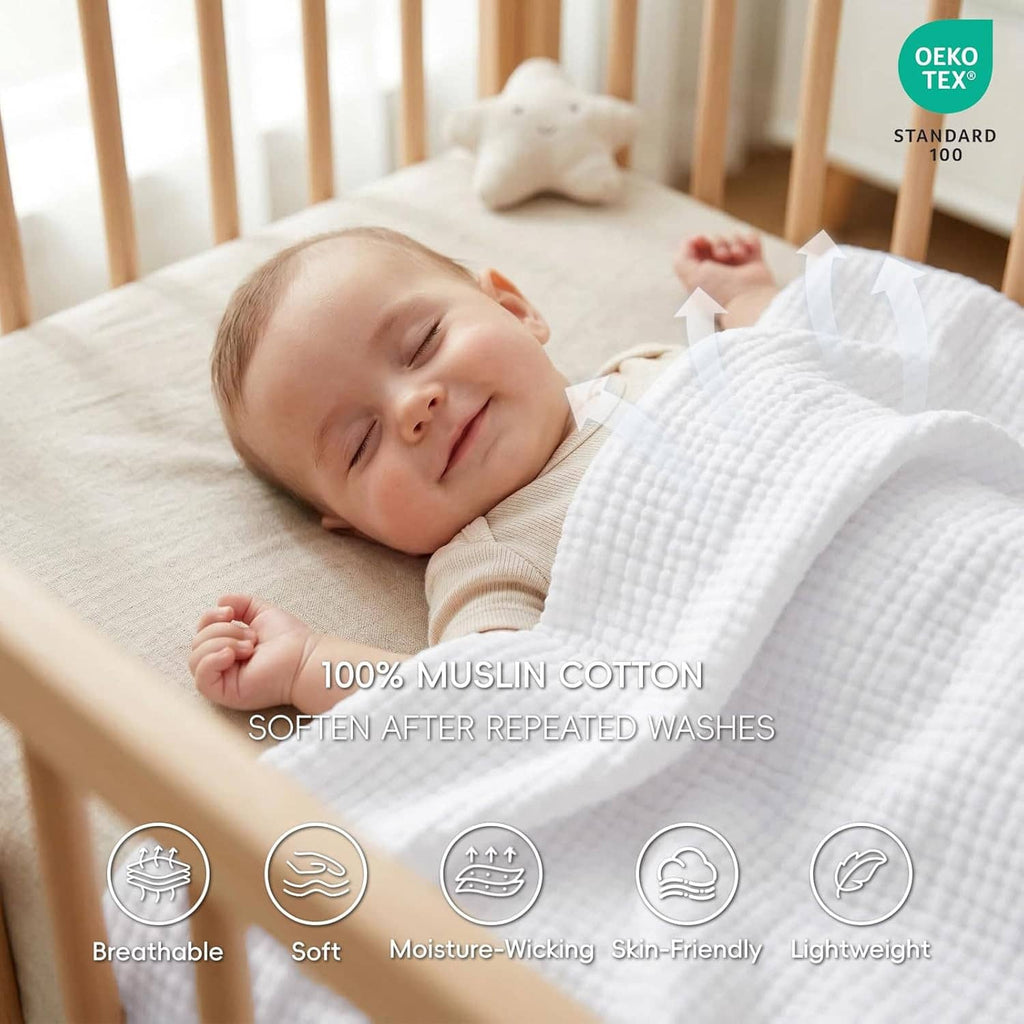 White muslin cotton blanket covering a baby on a crib mattress