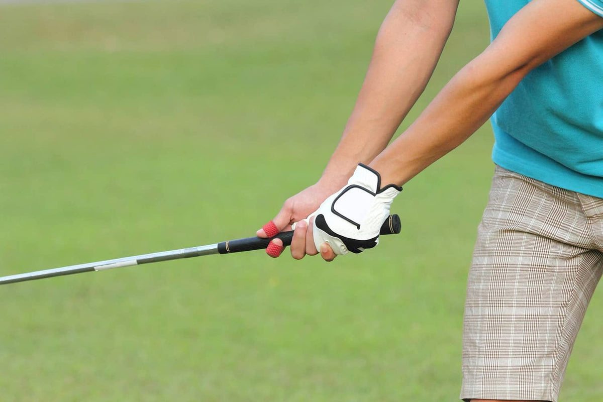 Red finger tip grip ring on golfer hand gripping a golf club handle