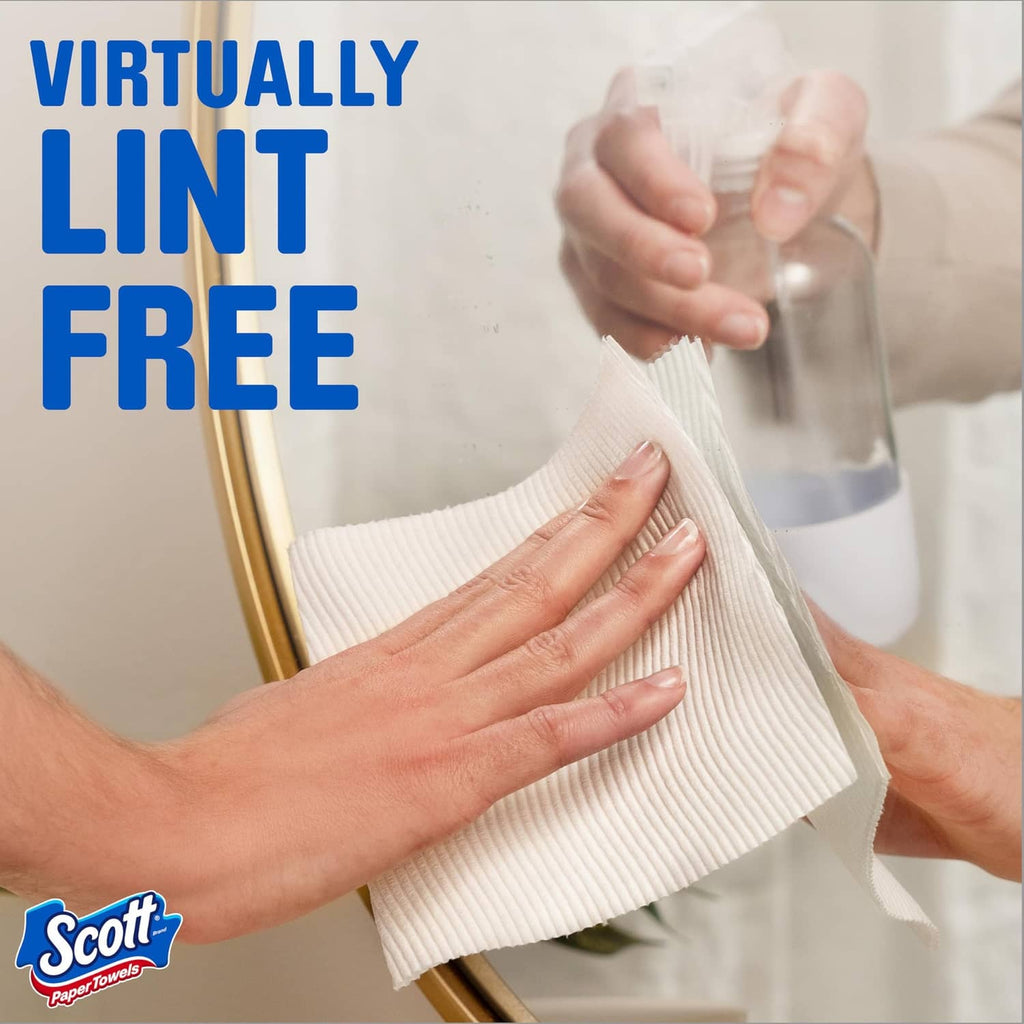 White Scott paper towel sheet wiping glass surface; hands pressing towel flat.