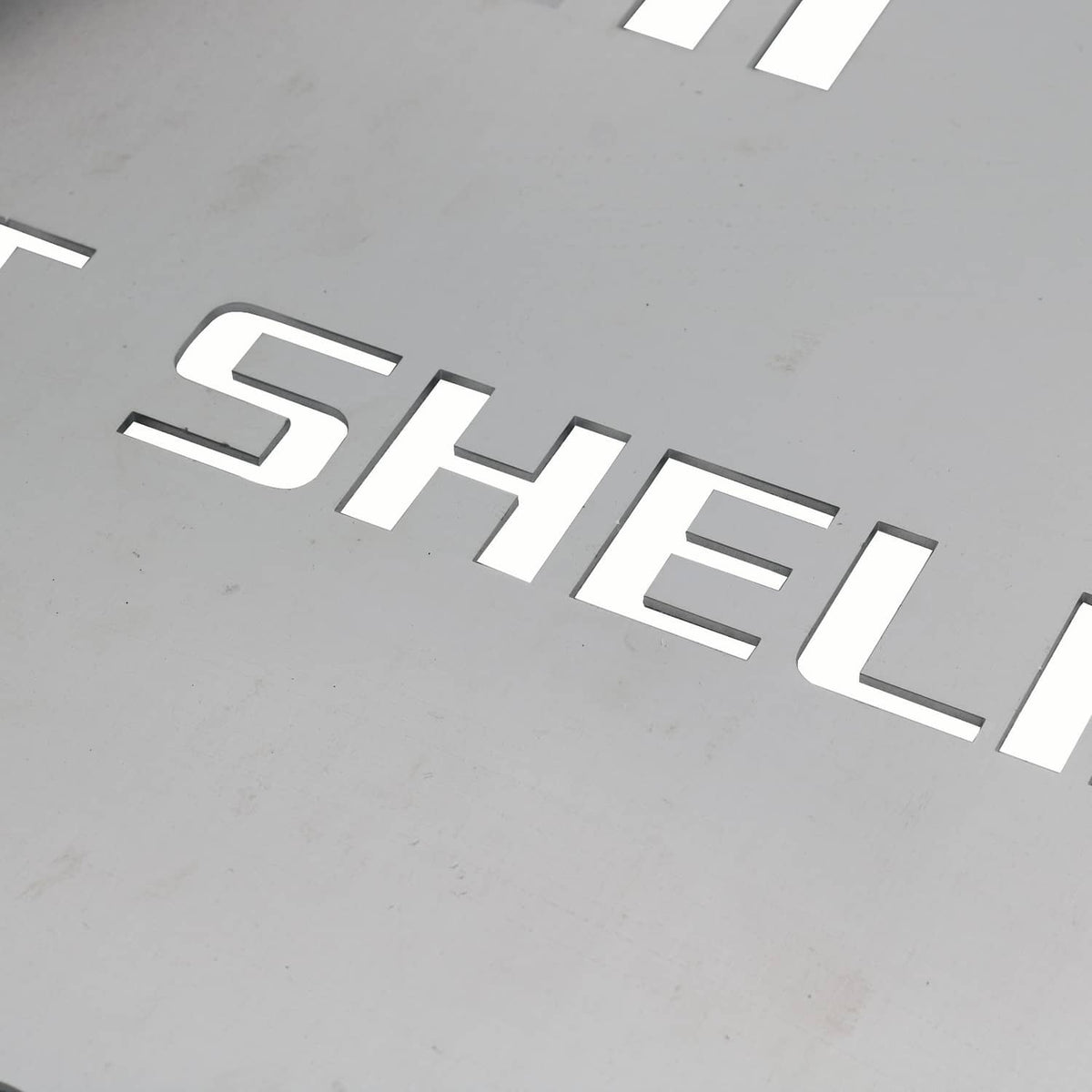 Close-up of stamped CAT SHELLI lettering on a metal catalytic converter shield
