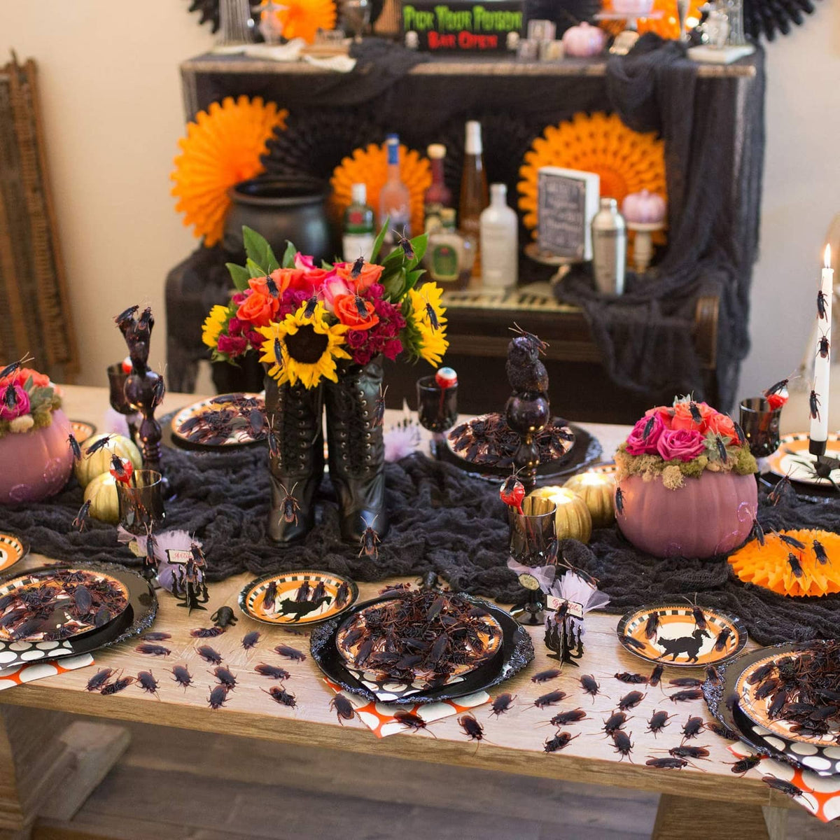 Fake dark insect figures on a table with decorative cupcakes and party plates