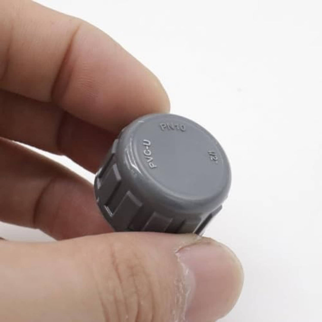 Grey PVC female thread cap plug held in fingers