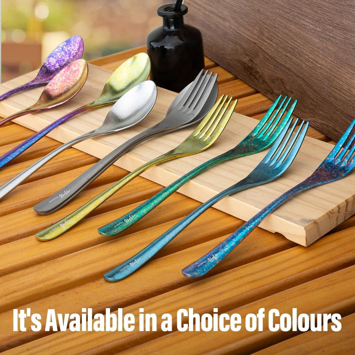 Titanium cutlery set with multicolor spoons and forks on a wooden board