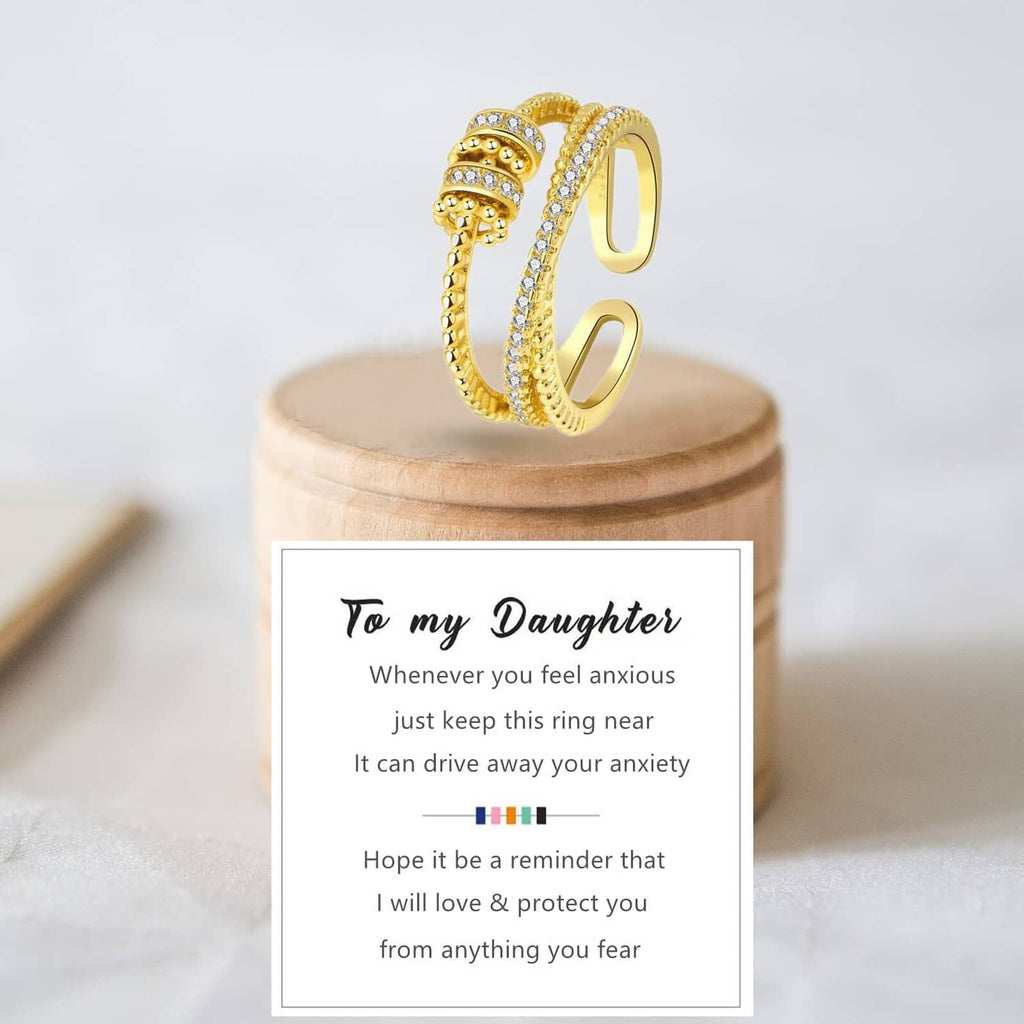 Gold-tone fidget ring with clear stone rows and textured bead band on a stand