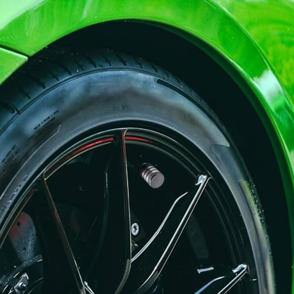 Grey metal tire valve stem cap with black inner insert on car wheel valve