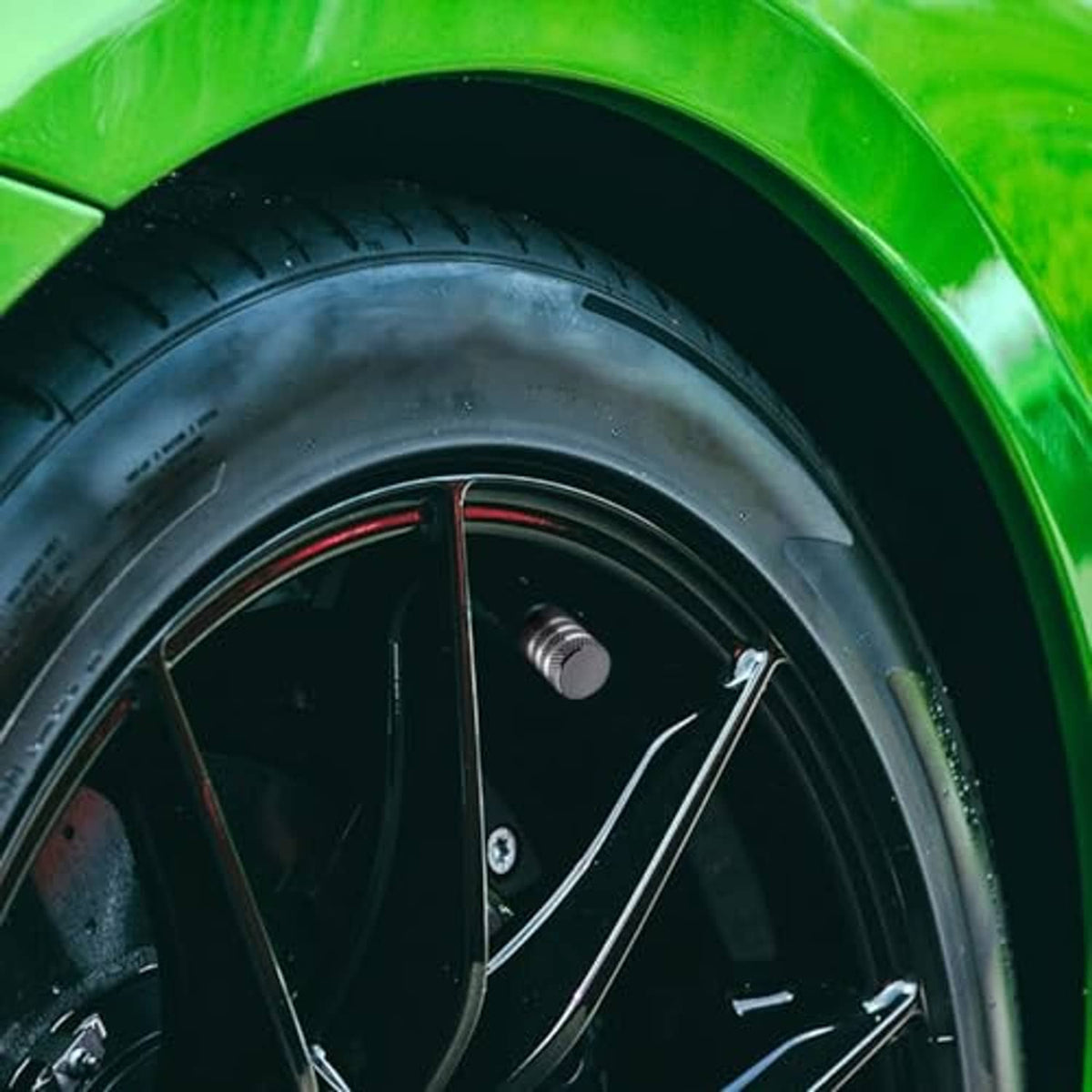 Grey metal tire valve stem cap with black inner insert on car wheel valve
