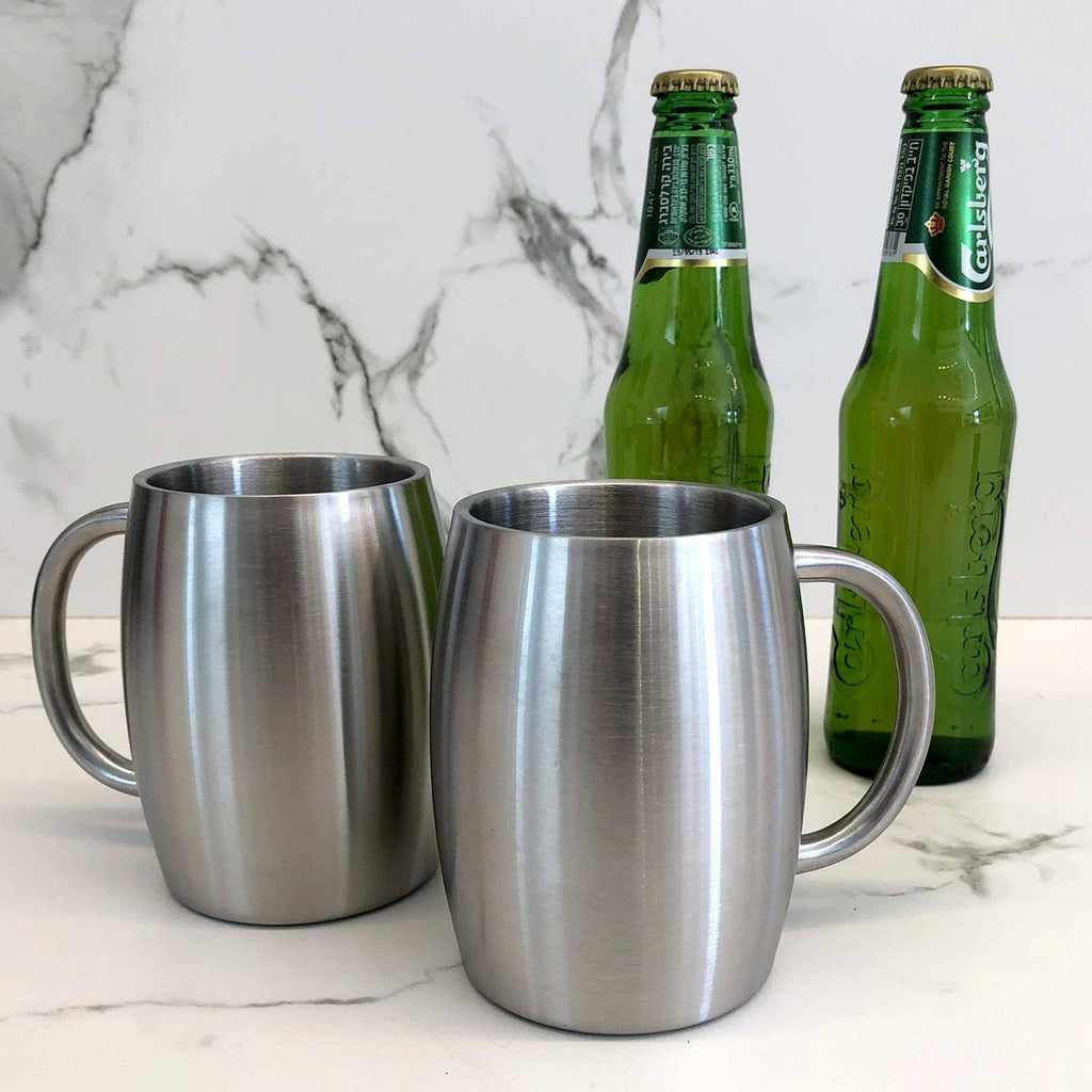 Pair of stainless steel insulated coffee mugs with curved handles, standing on countertop