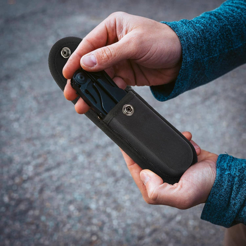 Black nylon pocket knife sheath with snap closure being opened by hand.