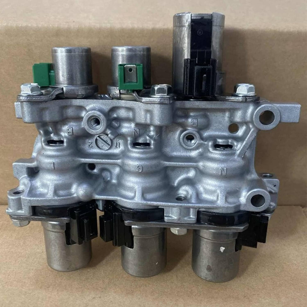 Transmission solenoid block assembly on cardboard background, silver housing with green parts