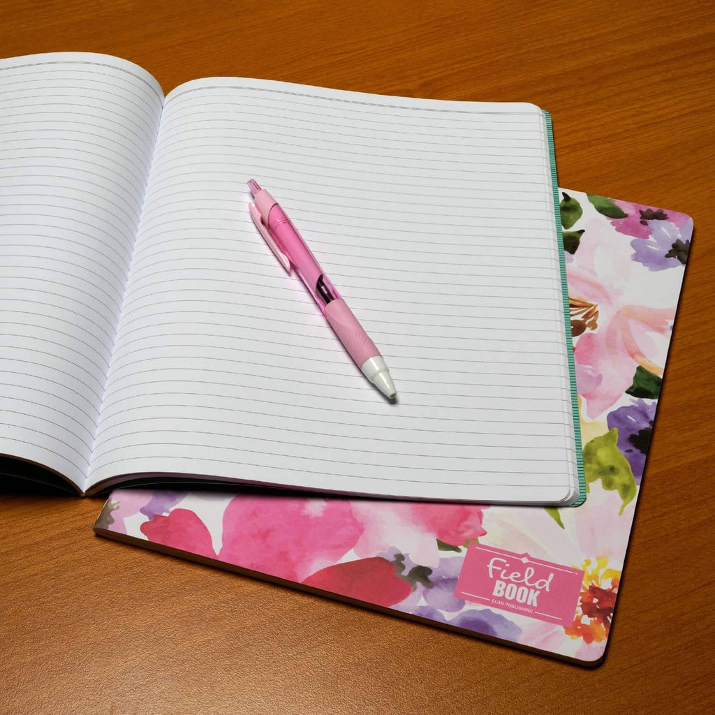 Lined memo notebook open with pen on pages, pink floral cover
