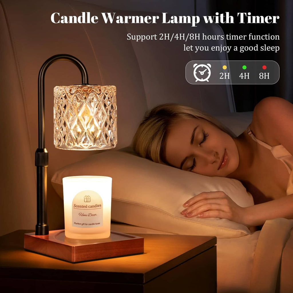 Black candle warmer lamp with faceted glass shade and lit wax candle beside bed