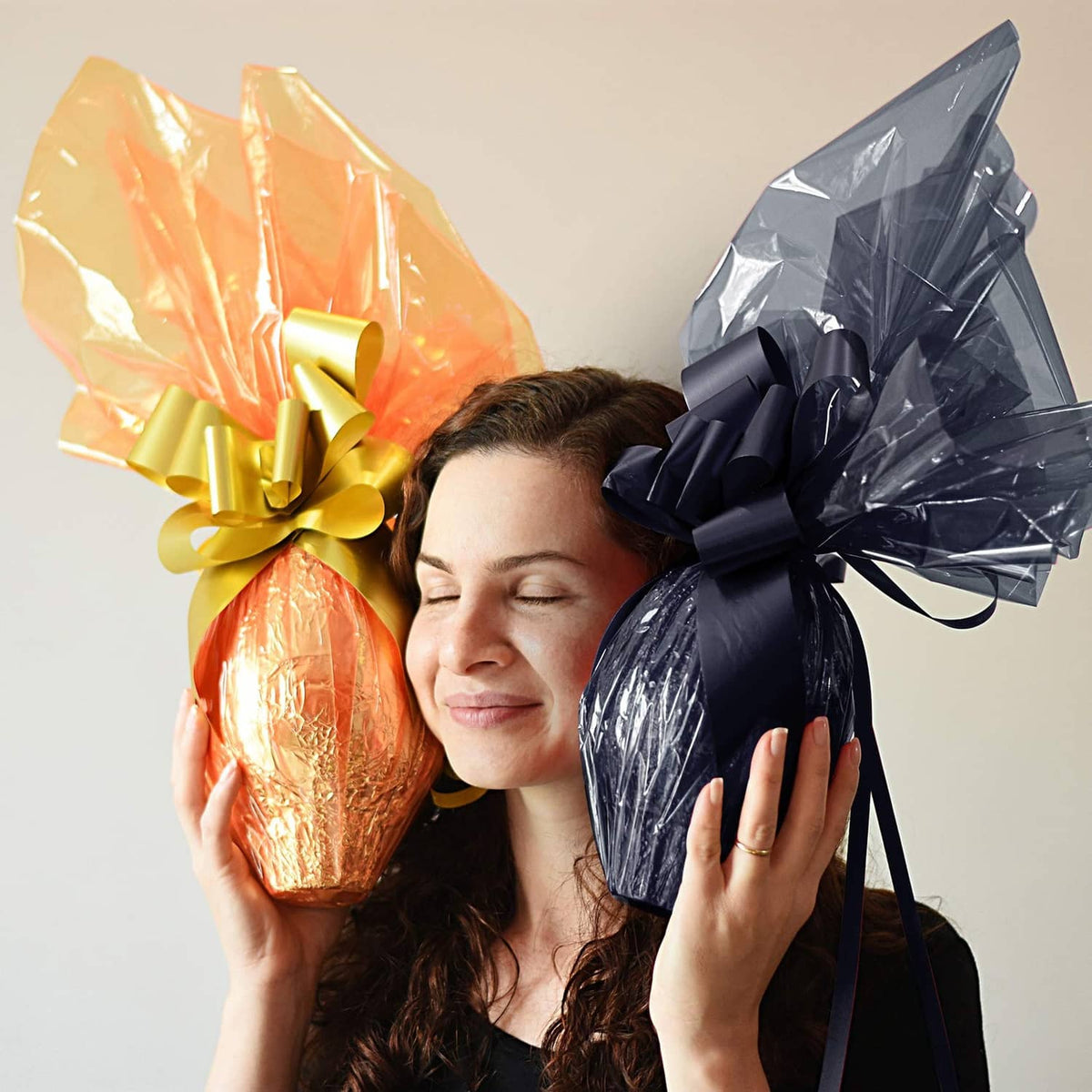 Dark translucent cellophane gift wrap bow tied around a wrapped egg-shaped item