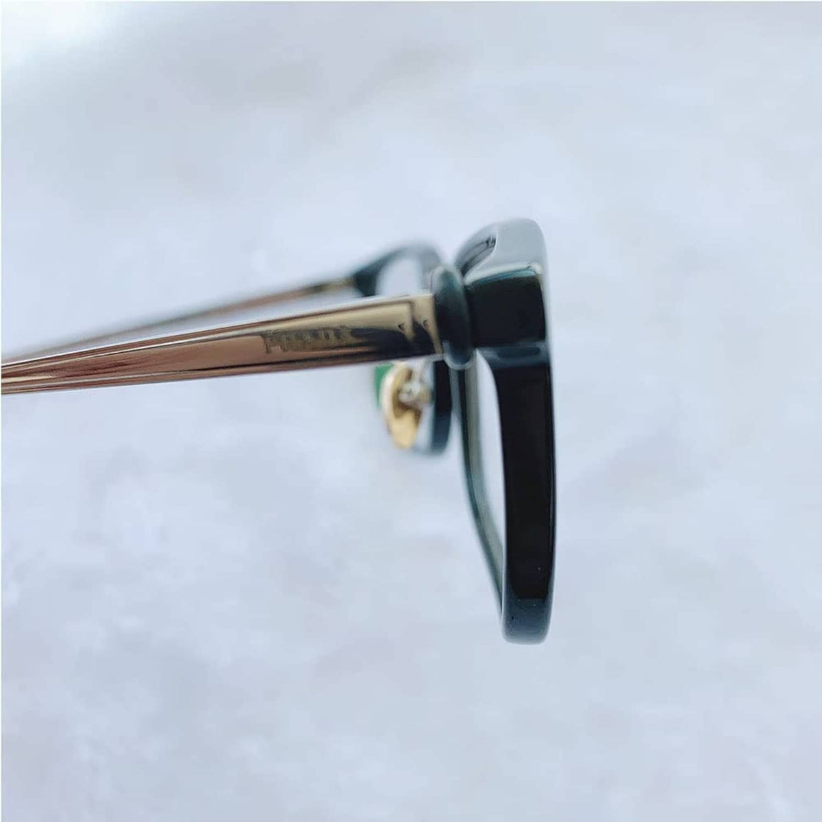 Eyeglass hinge tightener, black hinge clamp with gold screw detail