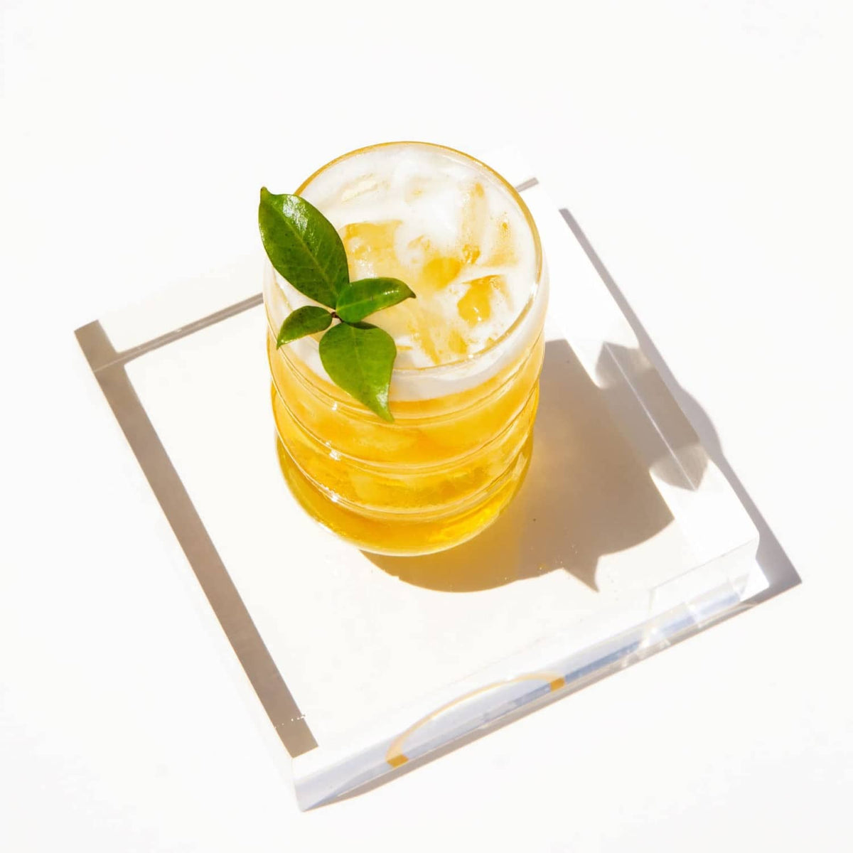 Glass of iced jasmine green tea with lemon-like slices and green leaves
