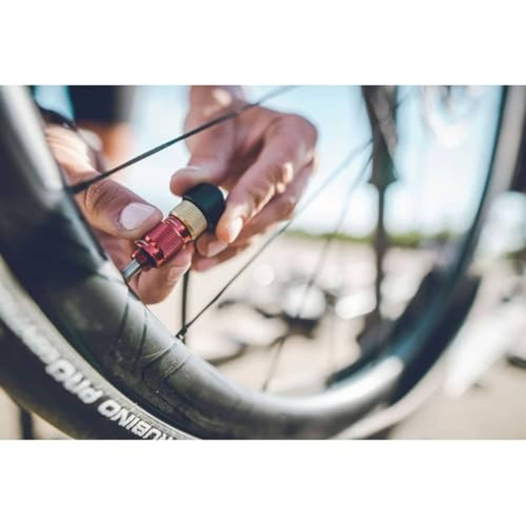 Bicycle valve chuck being attached to a wheel with a hand holding the brass head