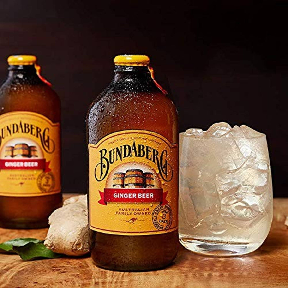 Bundaberg Ginger Beer bottles with a glass of amber drink on tabletop