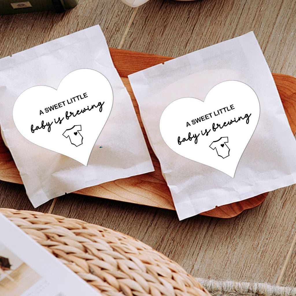 Heart-shaped “A SWEET LITTLE baby is brewing” stickers with baby onesie icon on bag