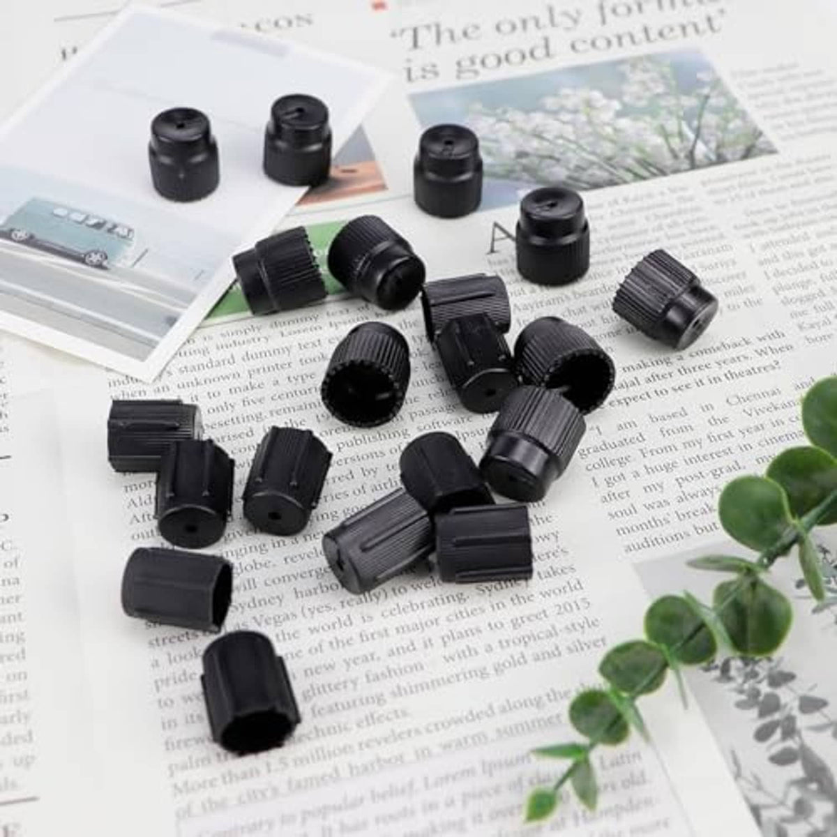 Black ribbed air conditioning valve core caps scattered on paper with a few accessories