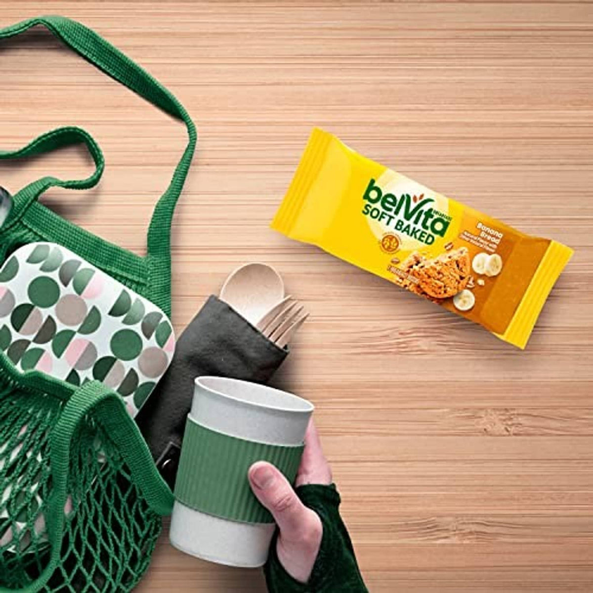 Belvita Soft Baked banana bread biscuit packs with a cup on a wooden table