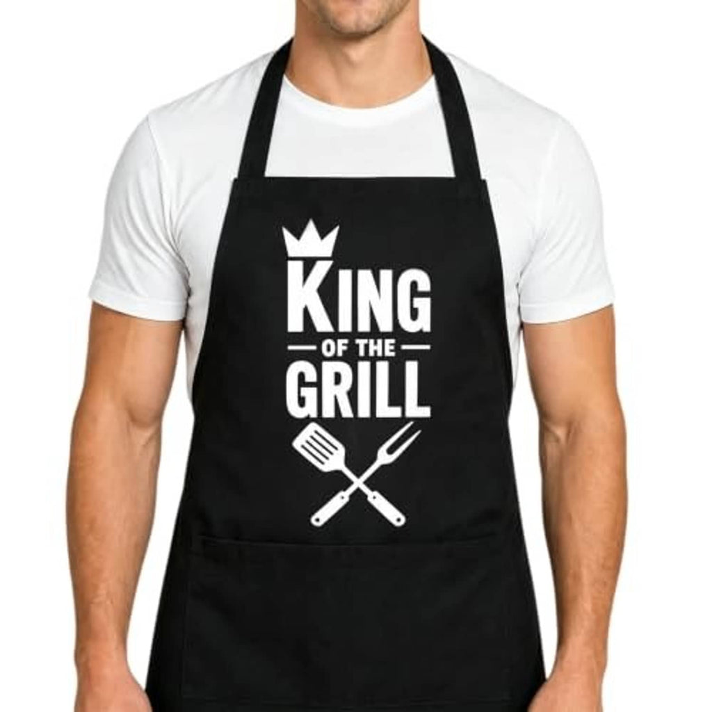 Black BBQ apron close-up with 'King of the Grill' crown logo and crossed utensils