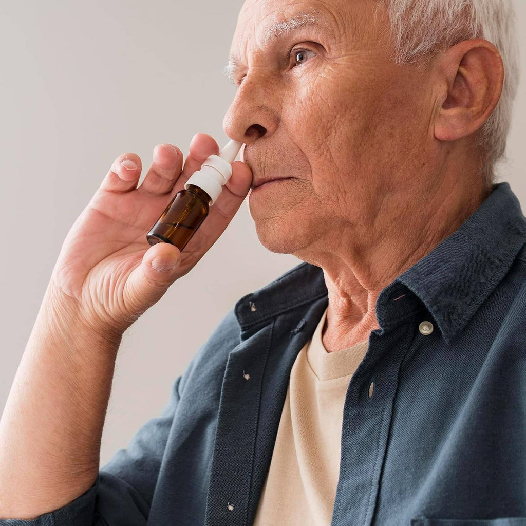 Elderly person using a small nasal spray bottle with white mist nozzle