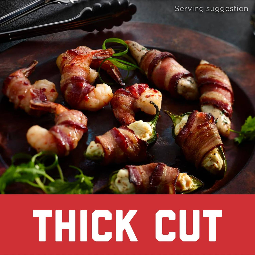 Thick cut cooked bacon pieces with visible fat stripes and small garnish on a pan