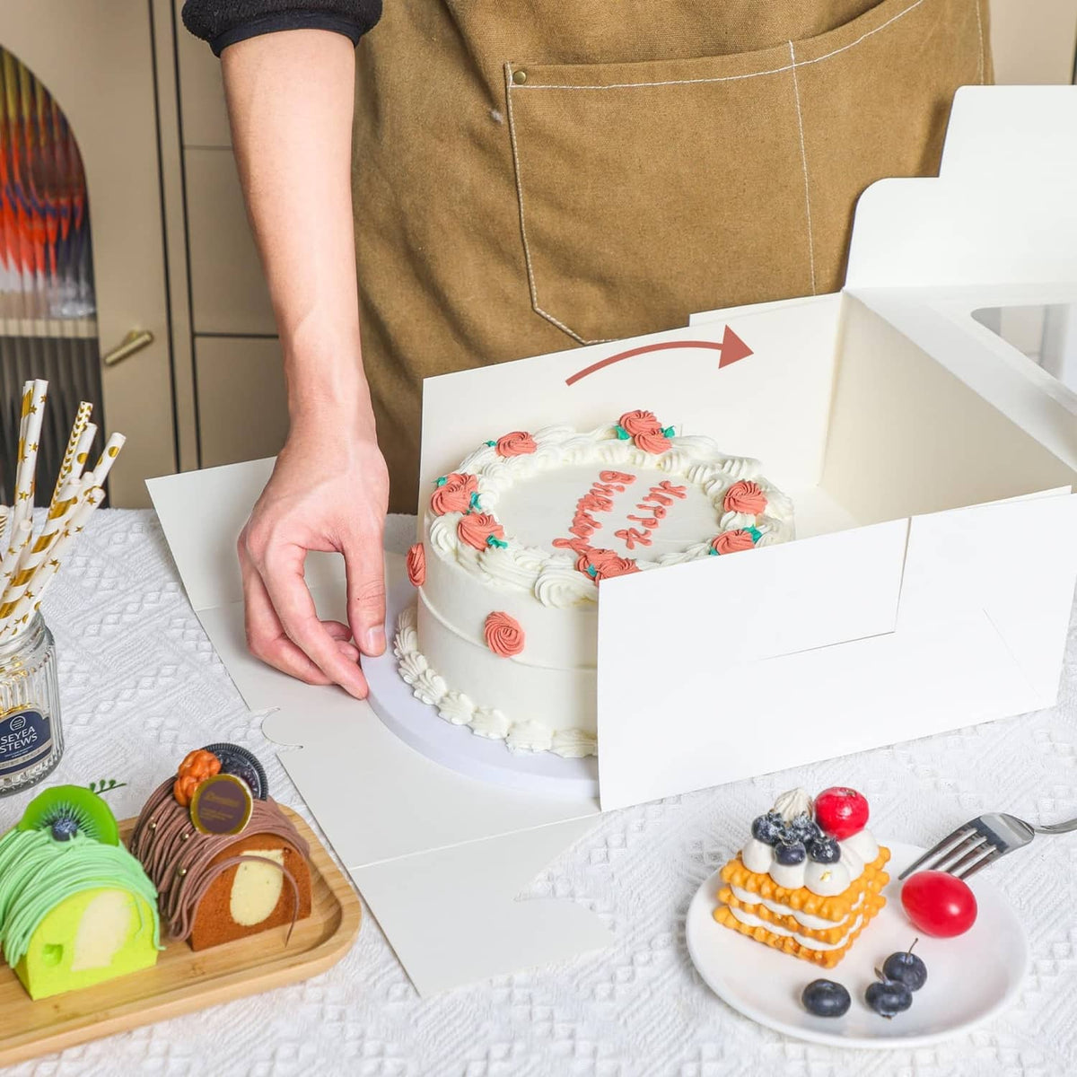 White square cake box with lid open while a decorated cake is placed inside.