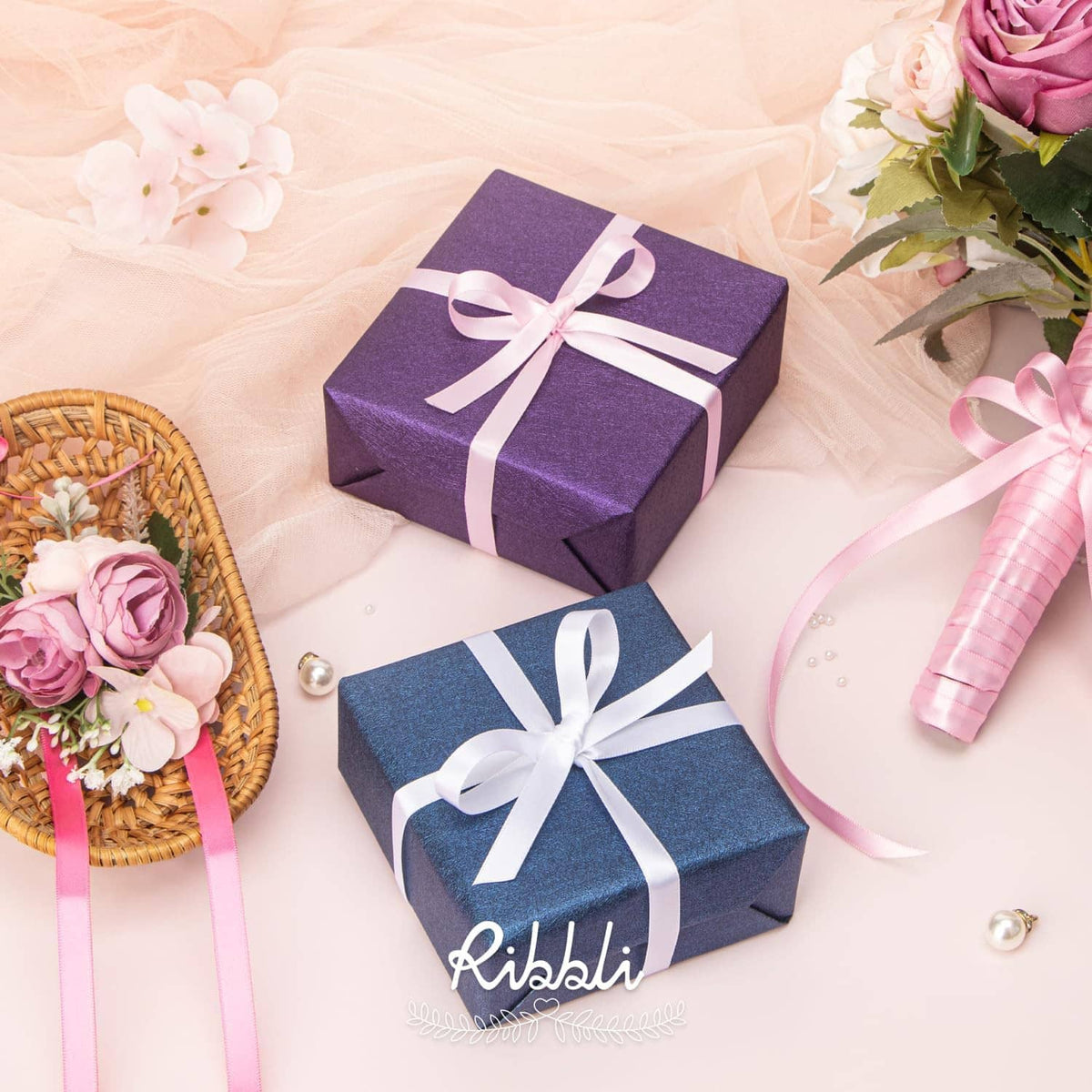 Gift boxes with pink satin ribbon bows and ribbon-wrapped item on soft fabric