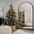 Arched full-length floor mirror with black frame and stand, full body reflection.