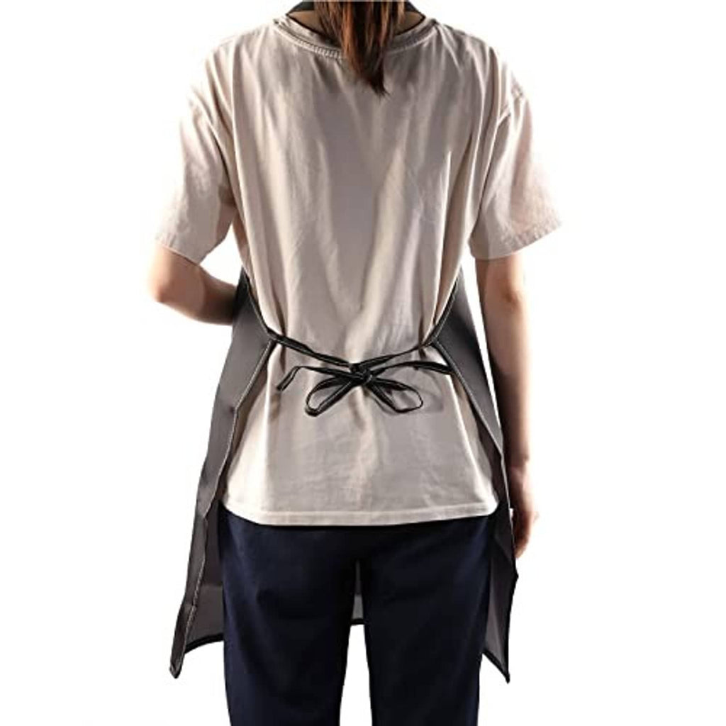 Black apron with waist tie and adjustable neck, worn over a light beige shirt.