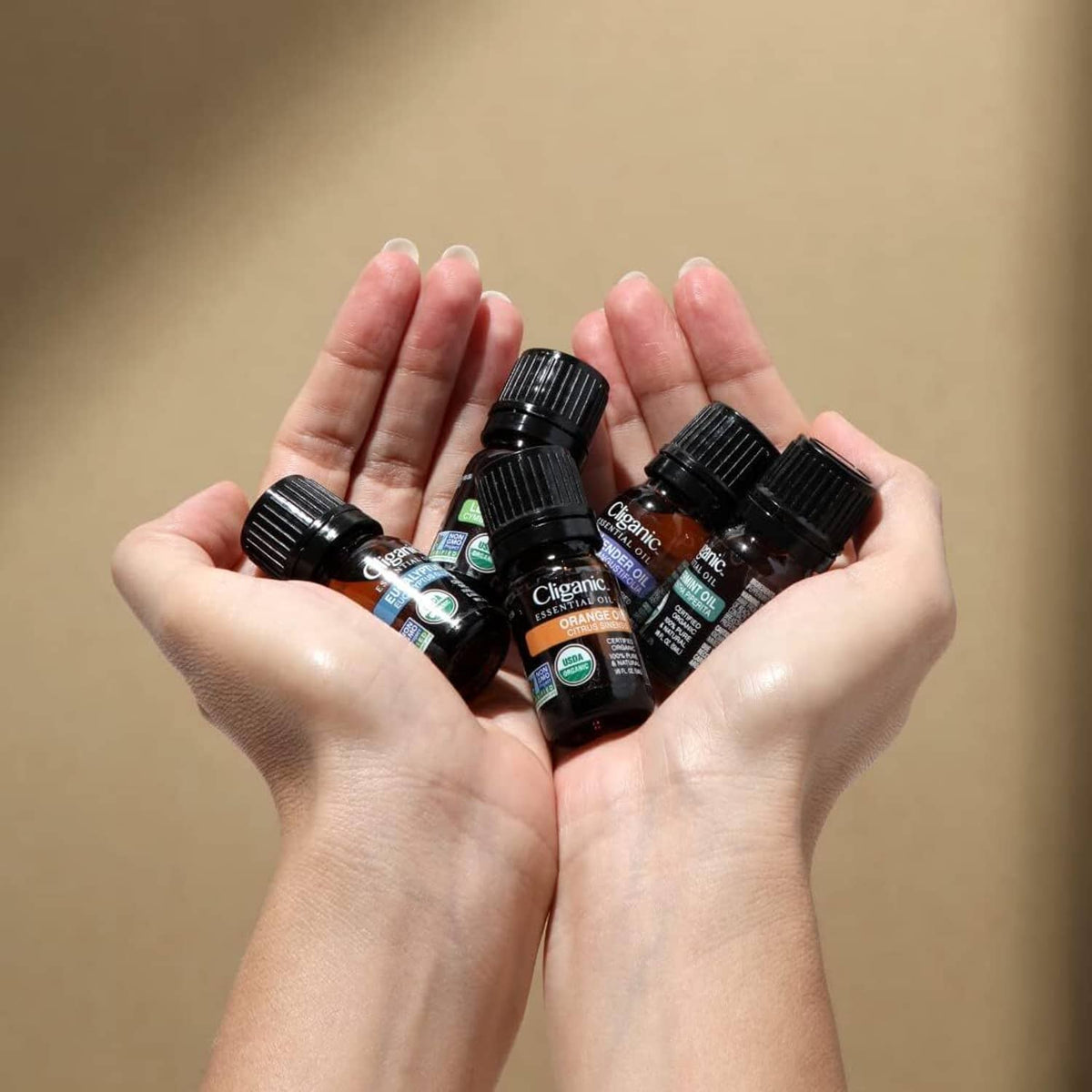 Lavender essential oil bottles held in two hands, small amber bottles visible.