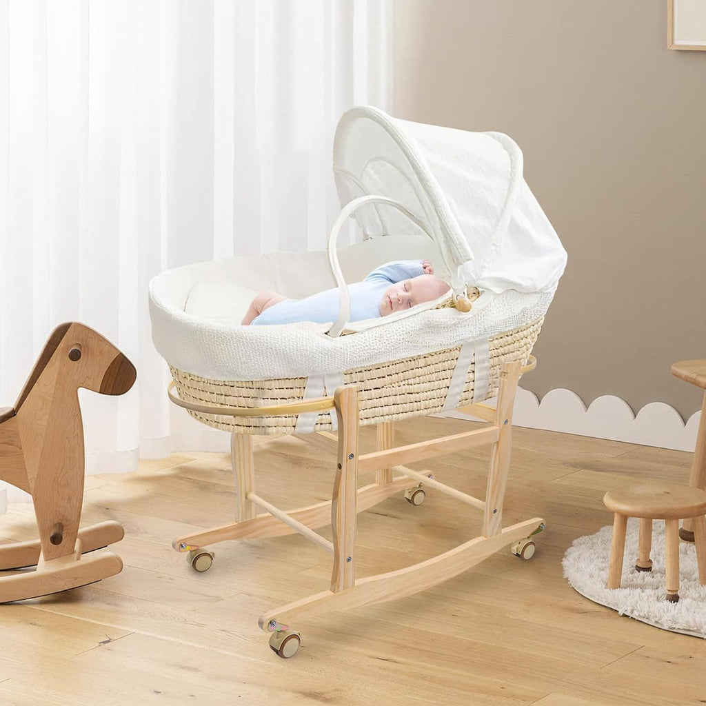 Wooden rocking Moses basket stand with woven basket holding a sleeping baby