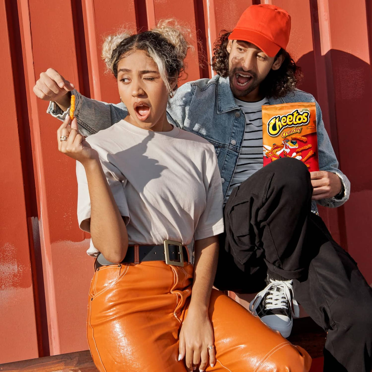 Orange crunchy cheese snack chips held with Cheetos bag in hand