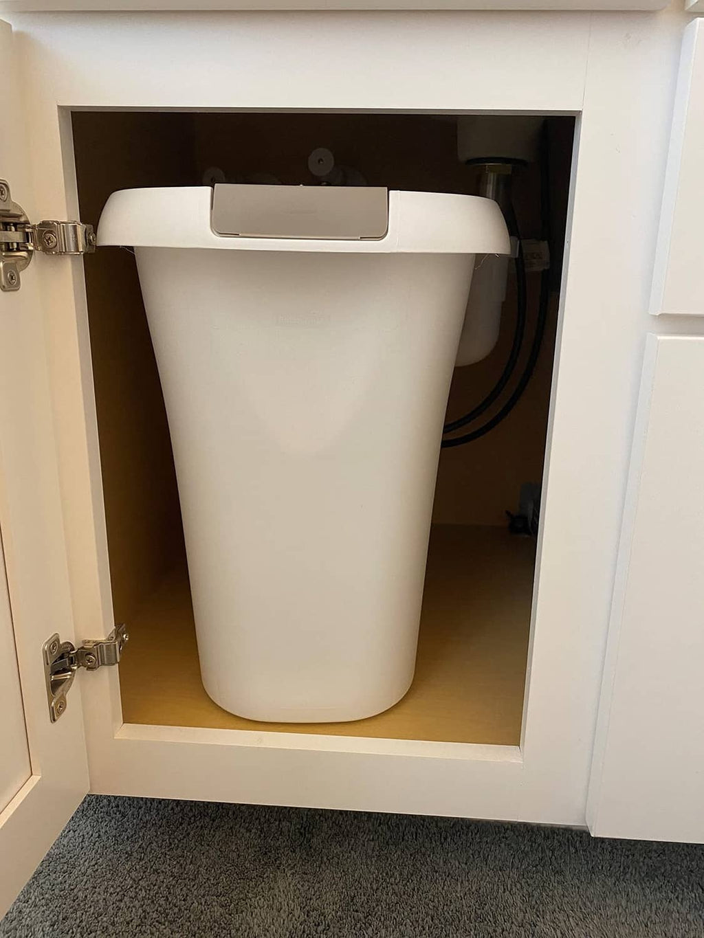 White plastic open-top trash can with gray lid in a recessed cabinet