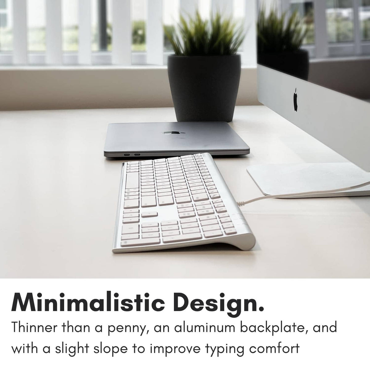Silver full-size wired keyboard with white keycaps on an aluminum platform