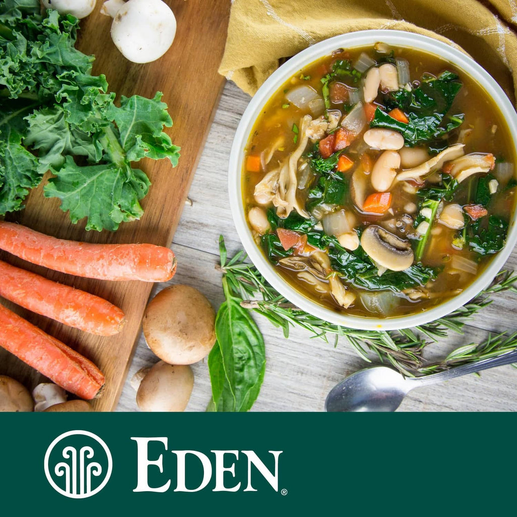 Bowl of white bean soup with leafy greens, carrots, and herbs