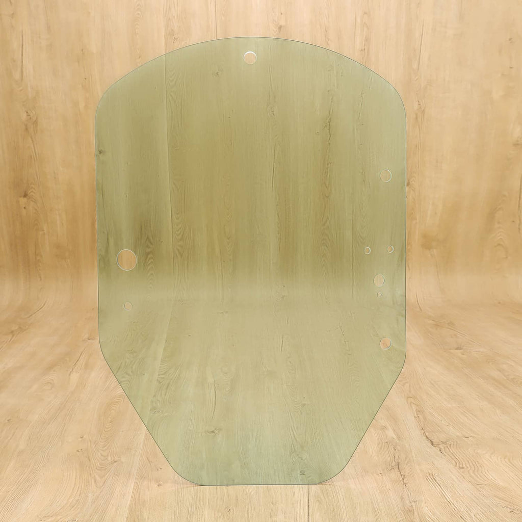 Green-tinted cab door glass panel with mounting holes; rounded, curved edges.