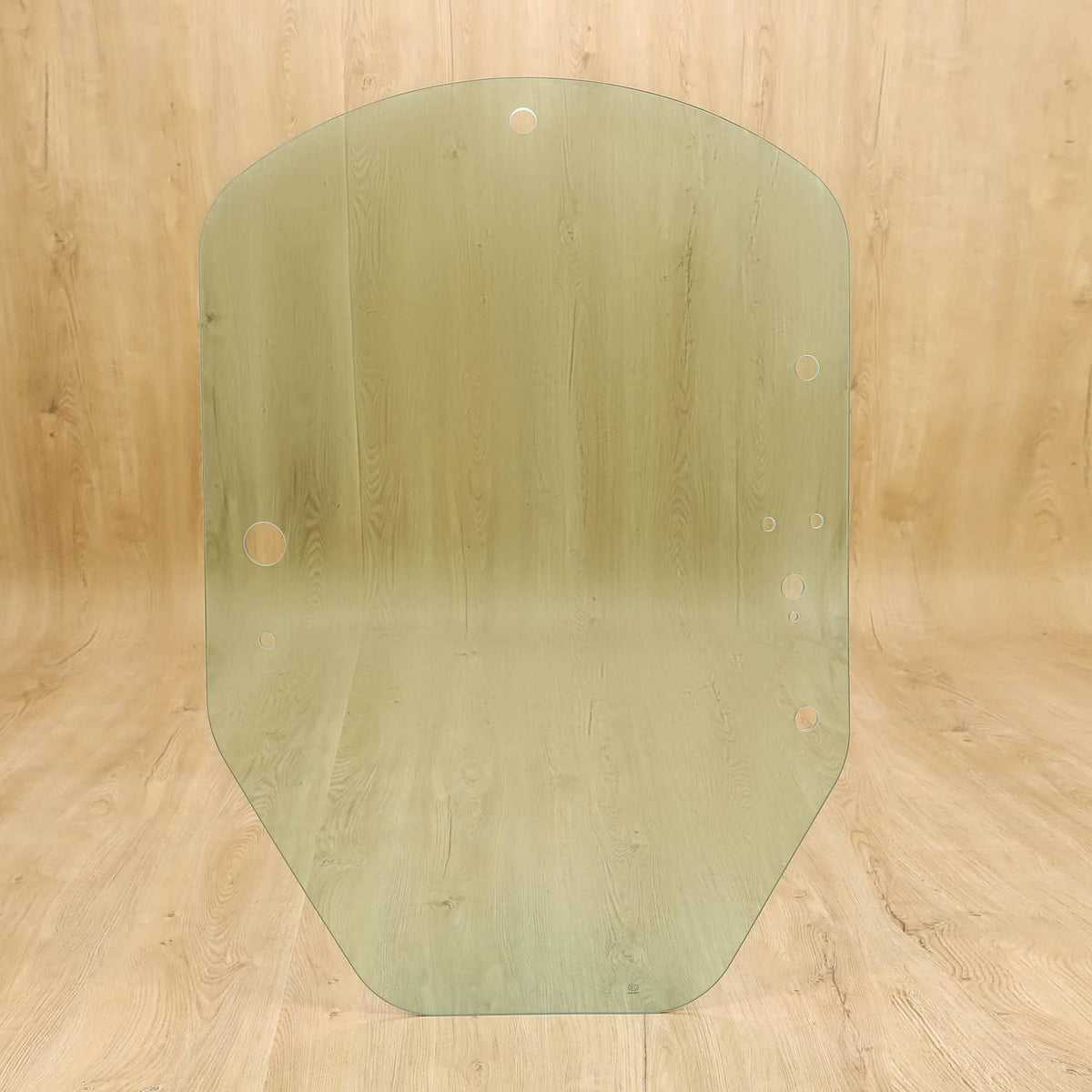 Green-tinted cab door glass panel with mounting holes; rounded, curved edges.
