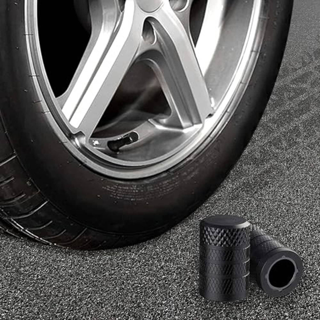 Black tire valve stem caps on gray pavement with car wheel in background, valve end visible